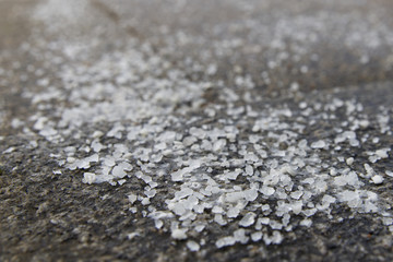 De-icing chemicals on the pavement. Pavement is sprinkled with technical salt or salt mixtures based on it, soft focus, copy space. Reagent - technical salt will make the road safe. 