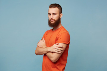 Strong serious manly guy hipster with a beard and a fashionable haircut wearing a red T-shirt...