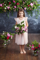 Portrait of the lovely little girl with a bouquet of flowers. Looking at camera.