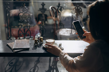 Attractive smiling girl taking photo cup of latte, using smartphone