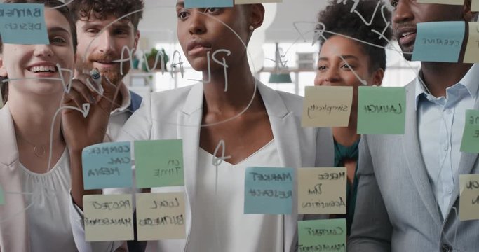 corporate business people using sticky notes brainstorming problem solving strategy on glass whiteboard team leader woman showing solution for project deadline in office meeting
