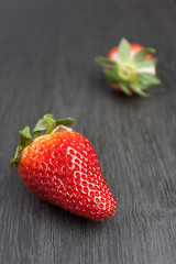 FRESAS ROJAS CON HOJAS VERDES SOBRE MESA DE MADERA GRIS OSCURO