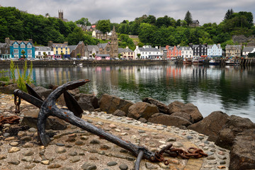 Rusted anchor on jetty and colorful houses reflected in the water of Tobermory harbour on the Isle of Mull Scottish Inner Hebrides Scotland UK