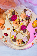 Vanilla Easter cake, in easter bunny shape, decorated with flowers and macaroons