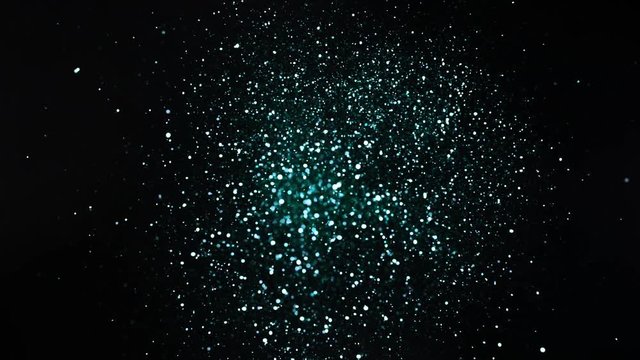 Green and silver glitter explosion in super slow motion on black background.
