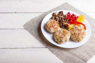 meatballs with rice mushrooms, sweet peppers and pomegranate seeds on white wooden background.