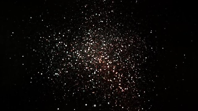 Red and silver glitter explosion in super slow motion on black background.