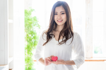 attractive asian woman holding heart symbol