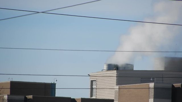 Top Of Hospital Building With Smokestacks And Electrical Power Lines In Front