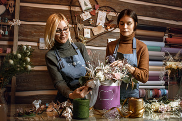 Gardener's in the flower shop make bouquet for a holiday. Family flower's business.  Lifestyle flower shop. Beautiful flower composition. Detail. Close up.