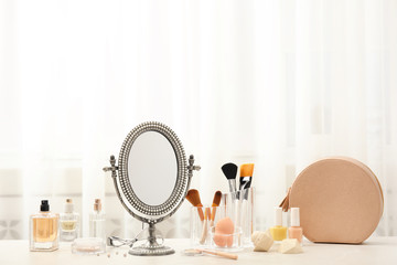 Mirror in antique frame and different cosmetics on dressing table, space for text. Beauty blogger