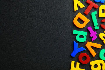 Plastic magnetic letters on black background, top view with space for text