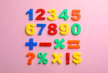 Colorful plastic magnetic numbers on color background, top view