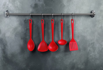 Rack with clean kitchen utensils on color wall