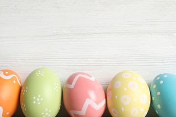 Colorful painted Easter eggs on wooden background, top view. Space for text