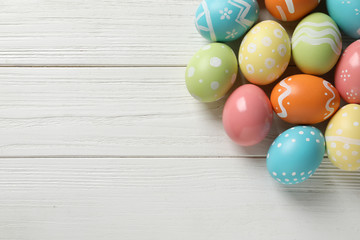 Many colorful painted Easter eggs on wooden background, top view. Space for text