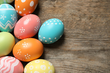 Many colorful painted Easter eggs on wooden background, top view. Space for text