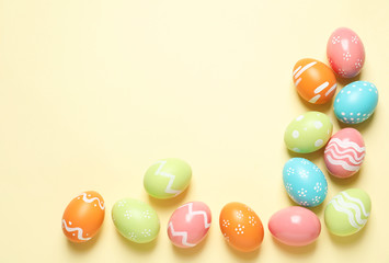 Fototapeta na wymiar Flat lay composition of painted Easter eggs on color background, space for text