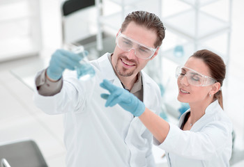 scientist and assistant look at the liquid in the flask