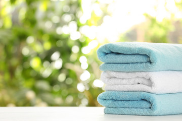 Stack of clean soft towels on table against blurred background. Space for text