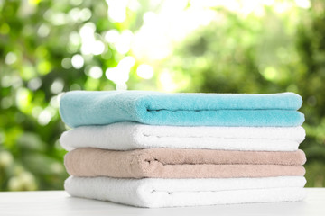 Fototapeta na wymiar Stack of clean soft towels on table against blurred background