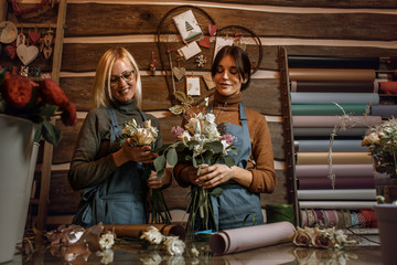 Gardener's in the flower shop make bouquet for a holiday. Family flower's business.  Lifestyle flower shop. Beautiful flower composition. Detail. Close up.