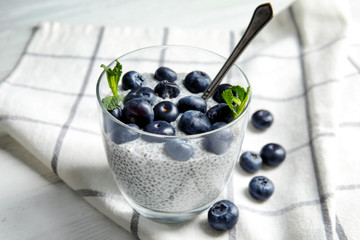 Tasty chia seed pudding with blueberries in glass on table