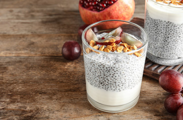 Tasty chia seed pudding with granola and ingredients on table. Space for text