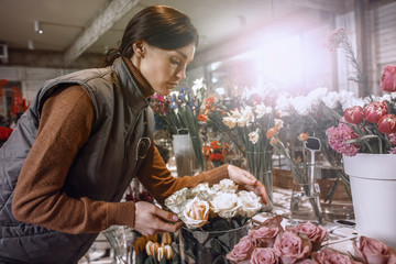 Woman - gardener in the flower shop make bouquet for a holiday. Family flower's business. Lifestyle flower shop. Beautiful flower composition. Love to flower's.Sunlight. Detail. Close up.
