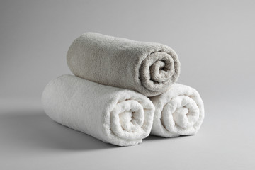 Fototapeta na wymiar Fresh soft rolled towels on light background