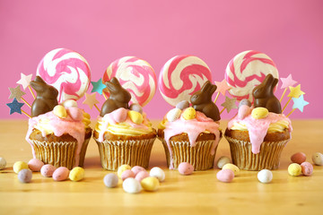 Easter theme candy land drip cupcakes decorated with chocolate bunnies in party table setting.