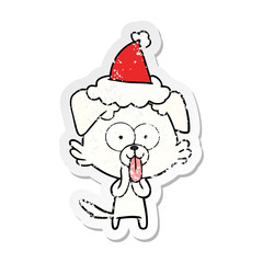 distressed sticker cartoon of a dog with tongue sticking out wearing santa hat