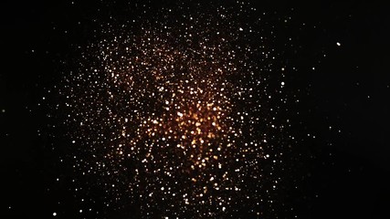 Golden glitter explosion in super slow motion on blacg background.