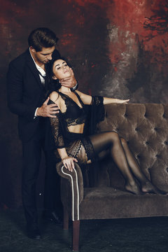 Elegant man in a black suit. Couple at home. Hot woman in a black underwear