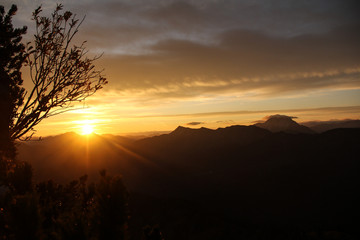 The first sun rays break through the mountains and clouds in the morning on the Tegernseer Hütte in the Bavarian Alps