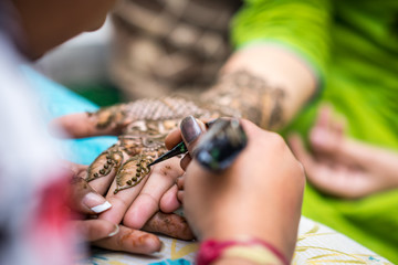 Woman gets traditional mehendi henna decoration for a Hindu wedding