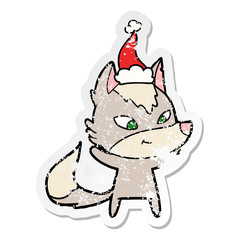 friendly distressed sticker cartoon of a wolf wearing santa hat