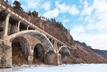 Baikal Lake. Historical Circum-Baikal Railway. View from the ice on the beautiful arched viaduct Upornaya Guba near the station Old Angasolka. Winter trips and excursions