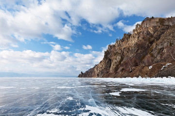 Fototapeta na wymiar Lake Baikal. Winter road on the ice of the lake along the Circum-Baikal Railway. The Cape Stolby is visible in the distance. Traveling by car on the ice of frozen lake