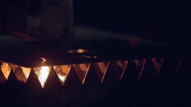 Modern programmed robot head cuts metal with sparks.