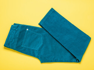 Beautiful green women's jeans on a yellow background.