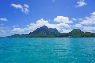 Landscape view of the island of Bora Bora in French Polynesia with the Mont Otemanu mountain surrounded by a turquoise lagoon - obrazy, fototapety, plakaty