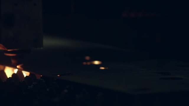 Modern programmed robot head cuts metal with sparks.