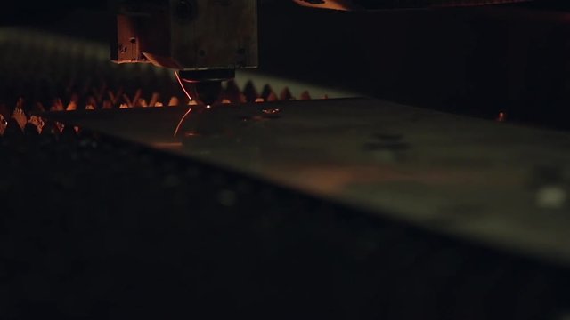 Modern programmed robot head cuts metal with sparks.
