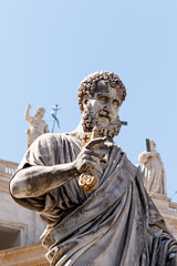 Statue of St. Peter in the Vatican with St. Peter's Basilica in the background and statues of the other apostles 