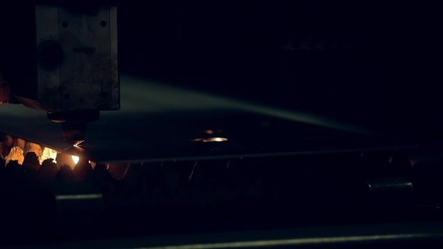 Modern programmed robot head cuts metal with sparks.