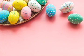 Easter traditions. Colorful Easter eggs in basket on pink background top view copy space