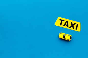 Taxi concept. Yellow service sign text taxi near car toy on blue background top view space for text