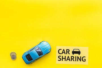Carsharing concept, carsharing sign. Economical, chip trip. Toy car near coins on yellow background...