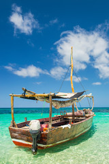 boat for walking in emerald sea under blue sky with clouds on Zanzibar island - obrazy, fototapety, plakaty